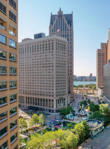 Stadtblick mit Hochhäusern, Straße, Bäumen und Parkfläche am Flussufer